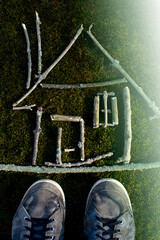 Aerial view of sticks arranged on grass to form geometric shapes and letters, showcasing outdoor creativity and nature art.