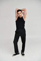 A man in black clothing poses against a white background.