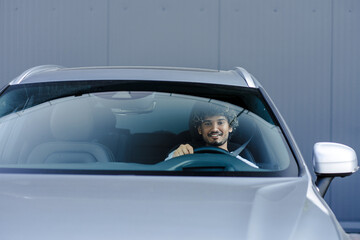 Young man smiling while driving modern car