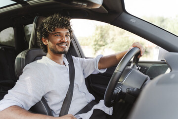 Smiling, Indian man smiling while driving modern car in the city