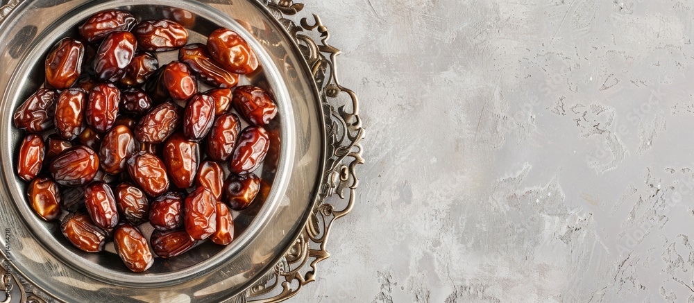 Poster Top view of dried dates placed on a shiny silver tray with empty space in the image for customization. Creative banner. Copyspace image
