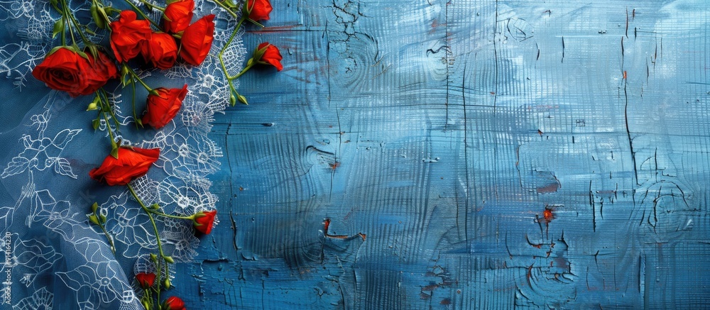 Poster top view of red flowers on a lace tablecloth over a blue wooden table with copy space image