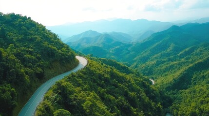 Fototapeta premium A winding mountain road surrounded by lush greenery, with a clear sky above and space for text. Perfect for adventure and travel themes.
