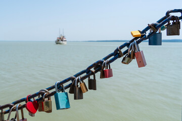 Padlocks on a harbor chain in a Balaton harbor with a ship in the background