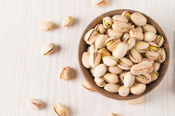 Organic roasted pistachio nuts in a wooden bowl. Top view. 