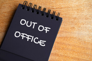 Top view of Out Of Office text on black notepad. Vacation of annual leave concept