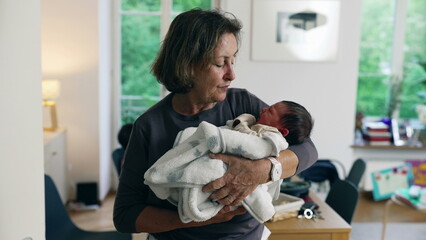 Grandmother holding newborn baby, wrapped in a cozy blanket, expressing warmth and affection, highlighting the intergenerational bond and nurturing care of family