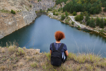 Redhead woman by a lake in an abandoned quarry
