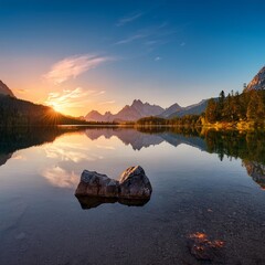 A tranquil lake at sunset with mountains in the background and a perfect reflection on the water