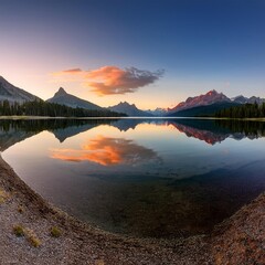 A tranquil lake at sunset with mountains in the background and a perfect reflection on the water