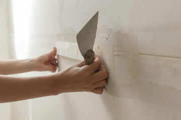Woman taping and mudding joins pieces of drywall into a single solid wall. Fixing dry wall surface...