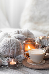 A cozy composition with threads, a candle and a cup of coffee. Hobby and home comfort concept.