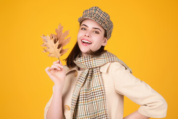 Studio isolated portrait of young happy woman with autumn fall leaves. Attractive caucasian smiling woman with yellow maple leaf. Autumn portrait of attractive woman wearing french beret ans scarf.