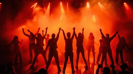 Dancers perform energetically against a backdrop of bright orange stage lights