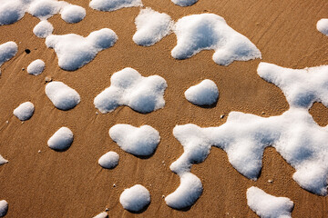 Small remnants of snow remains on the beach, following the previous evening snowfall and subsequent melting, forming small unconnected patterns at Harrington Beach State Park, Belgium, Wisconsin
