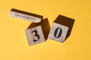 Wooden block calendar with the date december 30 on yellow background