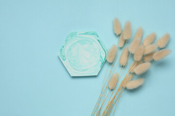 Hexagonal plaster tray with dry flowers on blue background. Top view