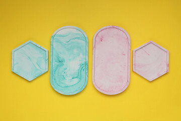 Hexagonal and oval plaster trays on yellow background. Top view