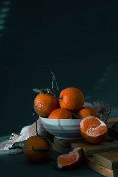 Small ripe oranges with leaves in a cream colored bowl, Fruits Light and Shade Photography