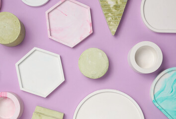 Set of Decorative pink plaster trays of different shapes on purple background with shadows. Stands for candles, organizers for cosmetics or jewelry. Top view