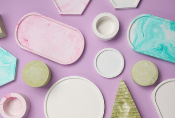 Set of Decorative pink plaster trays of different shapes on purple background with shadows. Stands for candles, organizers for cosmetics or jewelry. Top view