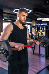An athlete with a barbell swings his arms in the gym. Sport lifestyle.
