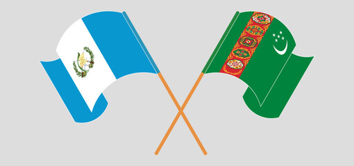 Crossed and waving flags of Republic of Guatemala and Turkmenistan