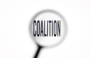 Word coalition on white screen through magnifying glass close-up
