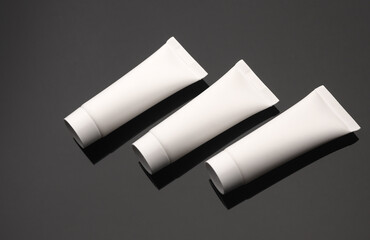 White tubes of cream on a black background