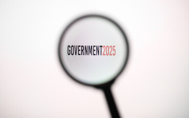 Phrase government 2025 on white screen through a magnifying glass.