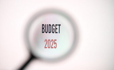 Phrase budget 2025 on white screen through a magnifying glass.