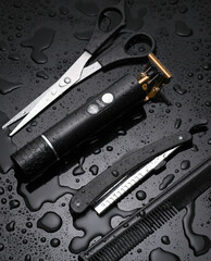 Fototapeta premium Trimmer with scissors, straight razor and comb on a black background with water drops. Barber tools