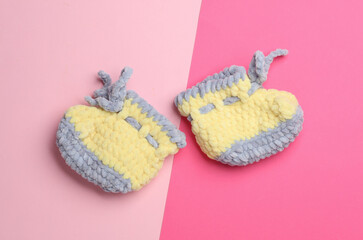 Knitted shoes for a newborn on a pink background