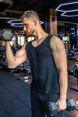 Obraz premium Athlete swings triceps with dumbbells in the gym. Healthy sports lifestyle.
