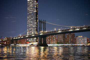 Fototapeta premium night view of manhattan behind the lace farms of manhattan bridge across east river 