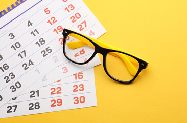 Eyelasses and calendar sheets on a yellow background