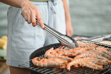 Fresh prawns sizzle on the grill, expertly handled with tongs, as they turn a perfect golden brown,...