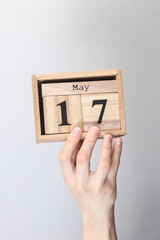 Wooden block calendar with date may 17 in hand on gray background