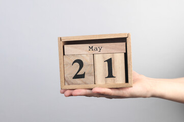 Wooden block calendar with date may 21 in hand on gray background