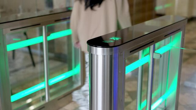 A confident businesswoman effortlessly passes through a modern turnstile using her personal access card in a sleek office lobby. Ideal for concepts of advanced security, workplace technology, and prof