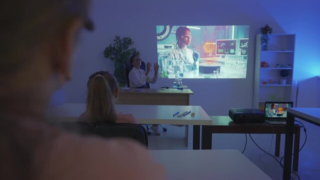 Junior school children in classroom on science chemistry lesson. Kids and teacher watch science program on video projector. Modern education concept