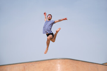 Obraz premium Young man performing choreography jumping in the air in a skate park