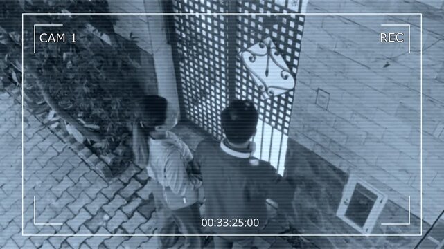 Surveillance camera view from above of young couple ringing doorbell on gate when having visit to friends