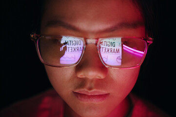 Portrait of person looking at screen with reflections on glasses displaying digital marketing text...