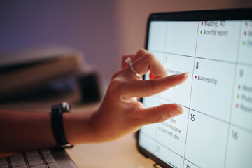 Closeup of a hand interacting with a digital calendar on a tablet screen, planning and organizing...