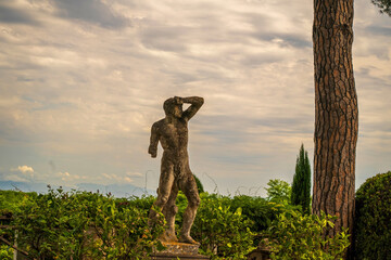 Fototapeta premium Ancient Stone Statue in Lush Garden with Cloudy Sky, , Gardens of Villa Cimbrone villa in ravello, Italy, Europe