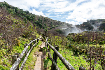 Wooden handrails and steps line the sulfurous steam vents at Furnas do Enxofre, Terceira Island, Azores, Portugal, creating a safe path through this otherworldly volcanic landscape.