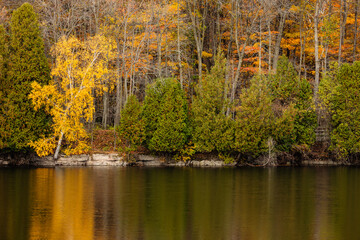 The autumn colors are changing on the shoreline along Quarry Lake at Harrington Beach State Park, Belgium, Wisconsin in late October