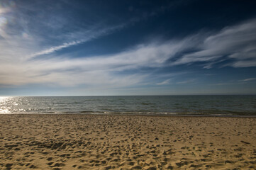 Empty, sandy beach by sunset under deep blue sky