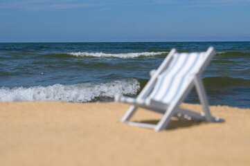 Unfocused empty sun lounger at a sandy beach. Back focus